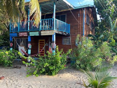 brown wooden two floor house surrounded by green pants and beach sand