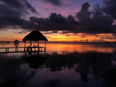 silhouette of thatch house and sunset by lagoon