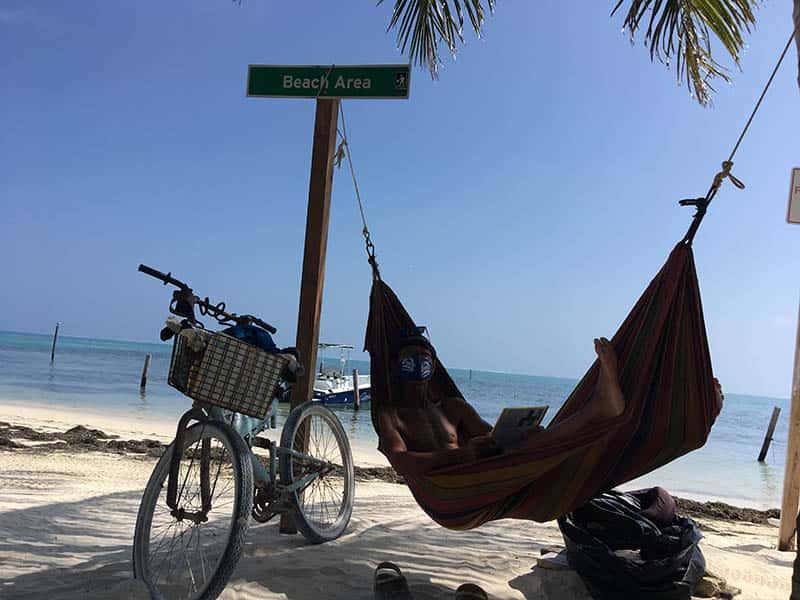 man chilling in at beach hammock with a mask