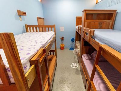 three sets of wooden bunkbeds along with two tiny fans