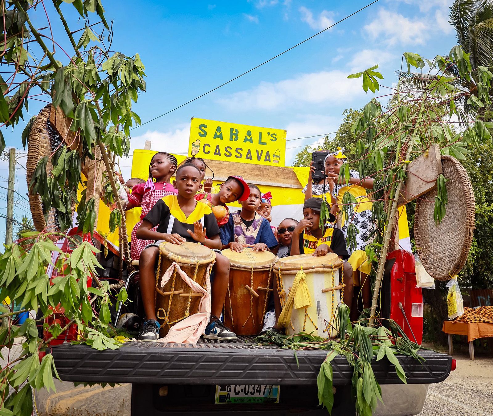 young garifuna kids playing drums behind a truck