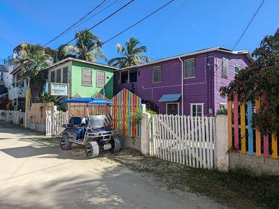 purple two story wooden house with golf cart parked in front