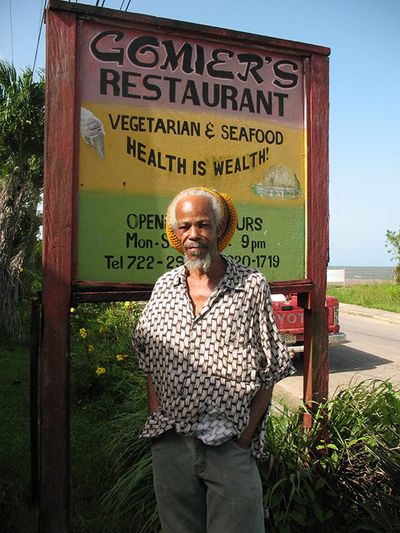 man with rasta hair in front of restaurant sign