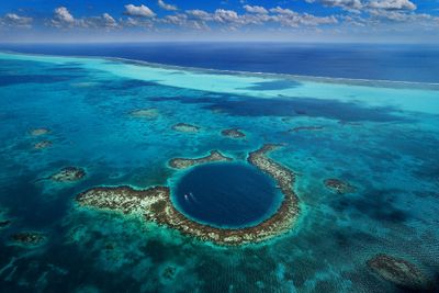 aerial shot of blue sinkhole with two boats inside it