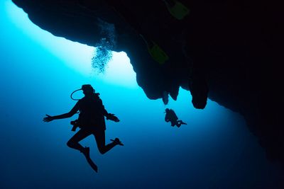 two scuba divers below cave structure