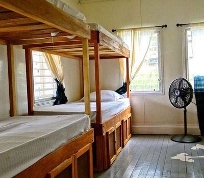 two wooden bunkbeds with a black fan on the side